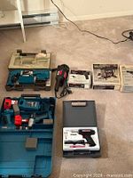 Overview of lot showing Makita cases, corded reciprocating saw, two boxed tools and solder gun case