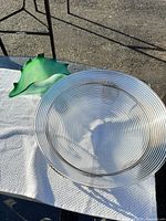 Green art glass bowl and portion of clear platter on tabletop