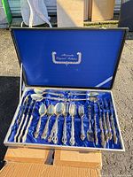 Open display case showing entire 48-piece flatware set in blue satin lining