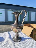 Full view of silver-tone ewer vase showing shape, handle, spout, base, and floral panel