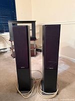 Front view of both floorstanding speakers with grilles attached and speaker cables visible