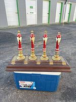 Front view showing four red wooden tap handles with brass bases mounted on wooden board