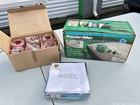 Iron box, open box of red napkin rings, sealed Noël napkins