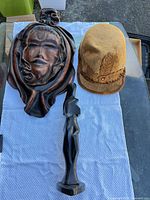 All three items laid out together on table: hat, wall plaque, black marble figurine
