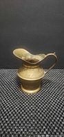 Side view of brass creamer pitcher showing engraved band and overall shape