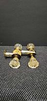 Two complete glass door knob sets with brass latches displayed on textured surface