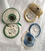 Three crochet pincushions open to show felt interiors, thimbles, pins and needles