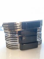 Four stacked chrome drawer pulls with black Bakelite inserts showing ribbed sides and rectangular insets