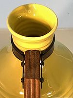 Top view showing yellow glaze, flared rim, wooden handle with metal mounts