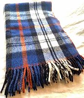 Folded plaid poncho blanket showing pattern and fringe