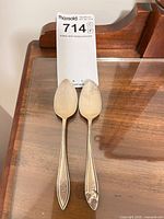 Front view of two engraved Birks sterling teaspoons, shows bent tip on right spoon