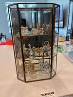 Overall view of brass-framed hexagonal glass cabinet containing multiple small crystal figurines