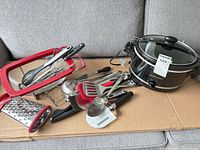 Group shot showing slow cooker with lid, strainer, box grater and utensils