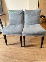 Front view of both grey upholstered dining chairs placed side by side