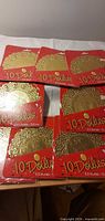 Eight sealed packs of gold paper doilies displayed