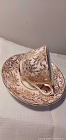 Cup resting on saucer showing exterior gold floral pattern