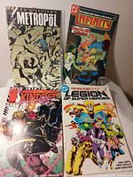 Front view of four bagged comic books: Metropol, Infinity Inc., The Kindred #2, Legion of Super-Heroes