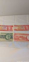 Fronts of two Barbados $1 notes and one Brazil 1 note