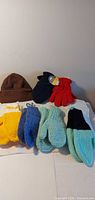 All items displayed: beanie, fleece gloves, four hand-knit mitten pairs