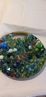 Top view of marbles spread on metal lid showing quantity and variety