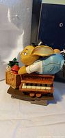 Side view of Pendelfin Stan figurine showing rabbit leaning over piano with tea crate and plant, original box in background