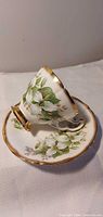 teacup resting on saucer showing floral design and gold trim