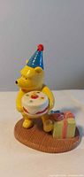 Front view of Pooh figurine holding cake and gifts