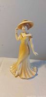 Front view of Royal Doulton figurine in yellow dress and hat