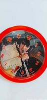 Front view of red-framed Elvis wall clock showing photo dial and numerals