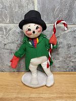 Front view of snowman doll standing on white base
