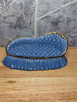 Front view of blue chaise lounge trinket dish on fluted base showing gold accents and tufted interior