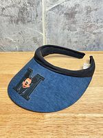 Left-front view of navy visor showing Mickey Mouse M graphic and black trim