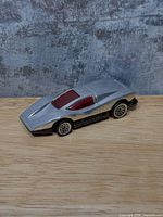 Side view of silver Hot Wheels Silver Bullet car showing body, wheels, red windows