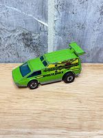 Left side view of lime green Hot Wheels Spoiler Sport car showing graphics and wheels