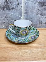 Teacup on saucer showing floral design, gold trim visible