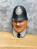 Front view of painted resin policeman wall bust on wood background