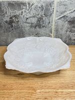 Top angled view of milk glass bowl showing scalloped rim and grape motif