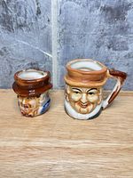 Front view of both ceramic figural character mugs