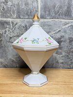 Full view of porcelain covered compote showing floral decals and gold finial