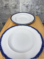 Two matching white shallow bowls with cobalt and gilt rim shown top view