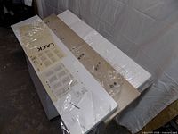 Three packaged LACK shelves, two white one light oak, with instructions visible