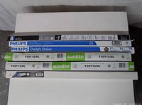 Stacked view of all five boxed fluorescent tubes showing brands and models
