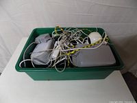 Green tub filled with tangled cables, adapters, devices