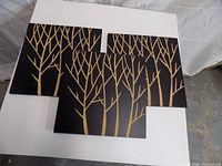 Front view of three black panels arranged to show gold tree design
