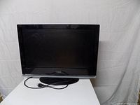 Front view of Vizio 26-inch TV with power cord on pedestal stand