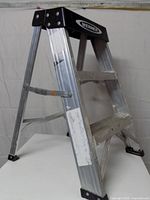 Left side view of Werner aluminum 3-step A-frame ladder standing open