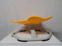 Side view of yellow plastic tilted seat on gray metal frame