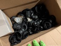 Box filled with numerous black plastic lamp sockets