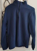 Full view of blue quarter-zip sweatshirt on hanger