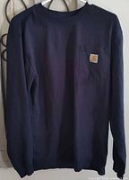 Front view of navy Carhartt long-sleeve shirt on hanger